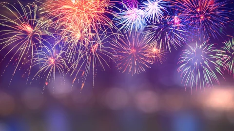 Feu d'artifice nocturne spectaculaire avec multiples explosions colorées illuminant un ciel violet